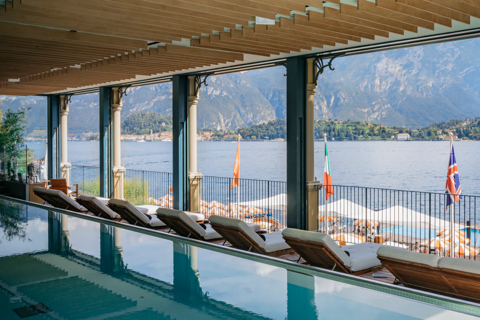 La piscina della T Spa con i lettini e le bandiere, e il lido oltre la vetrata