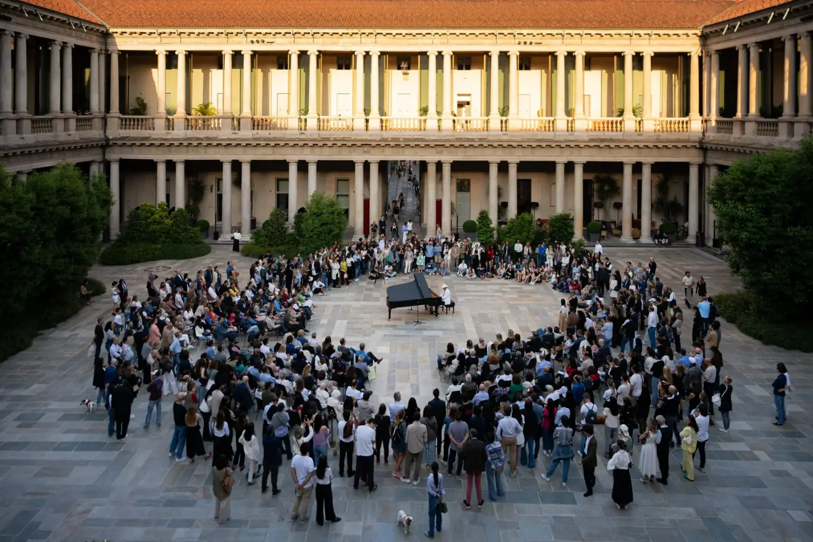 A piano performance with an audience in the Piazza of Portrait Milano
